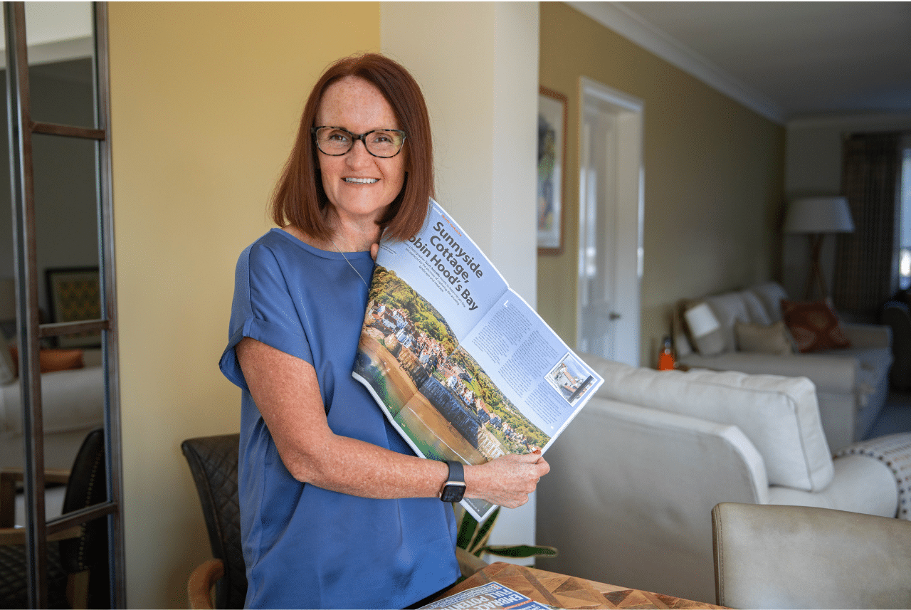 Rachel Spencer holding a magazine featuring press coverage of Sunnyside Cottage in Robin Hood’s Bay, used as an example of successful PR for pet businesses.